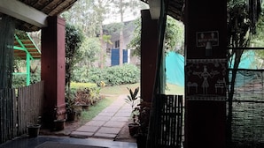 An entrance with a covered pathway leading to a garden area, a trash bin, and a washroom sign.