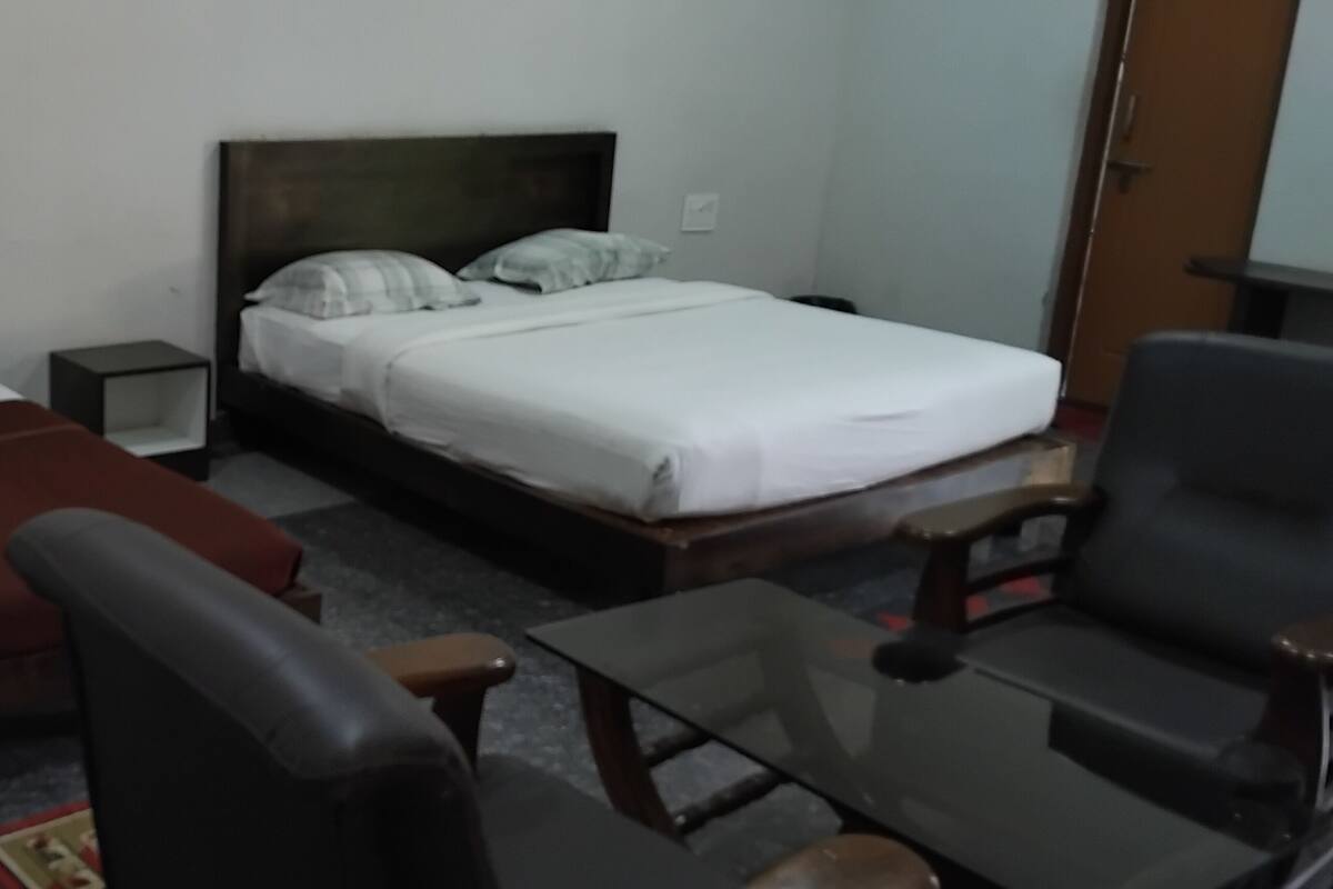 A hotel room with two beds, a sofa, a small table, and a chair.