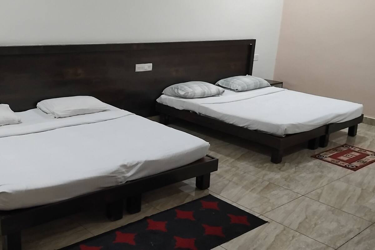 Two single beds with wooden headboards, white bedding, and a red and black patterned rug.