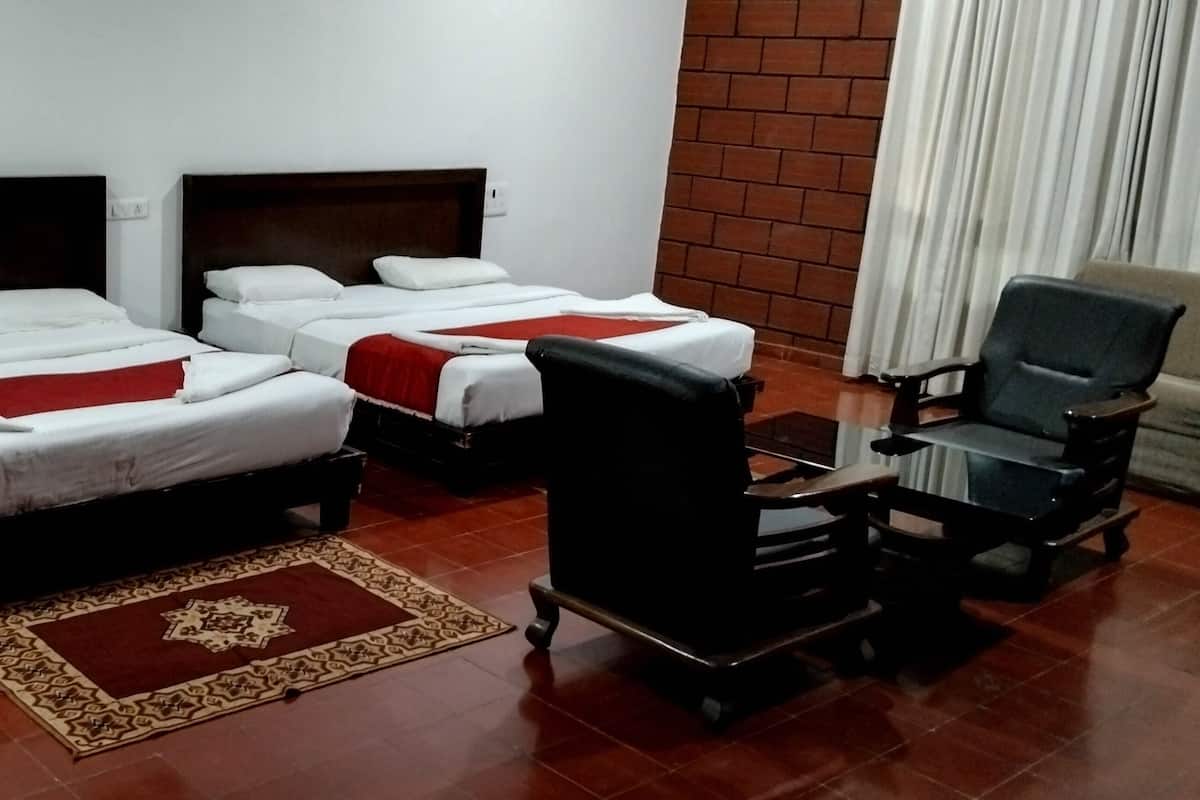 A hotel room with two beds, a red and white patterned rug, a black chair, and a brick wall.