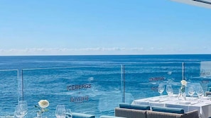 Un espace repas avec des tables dressées pour le dîner, donnant sur la mer.