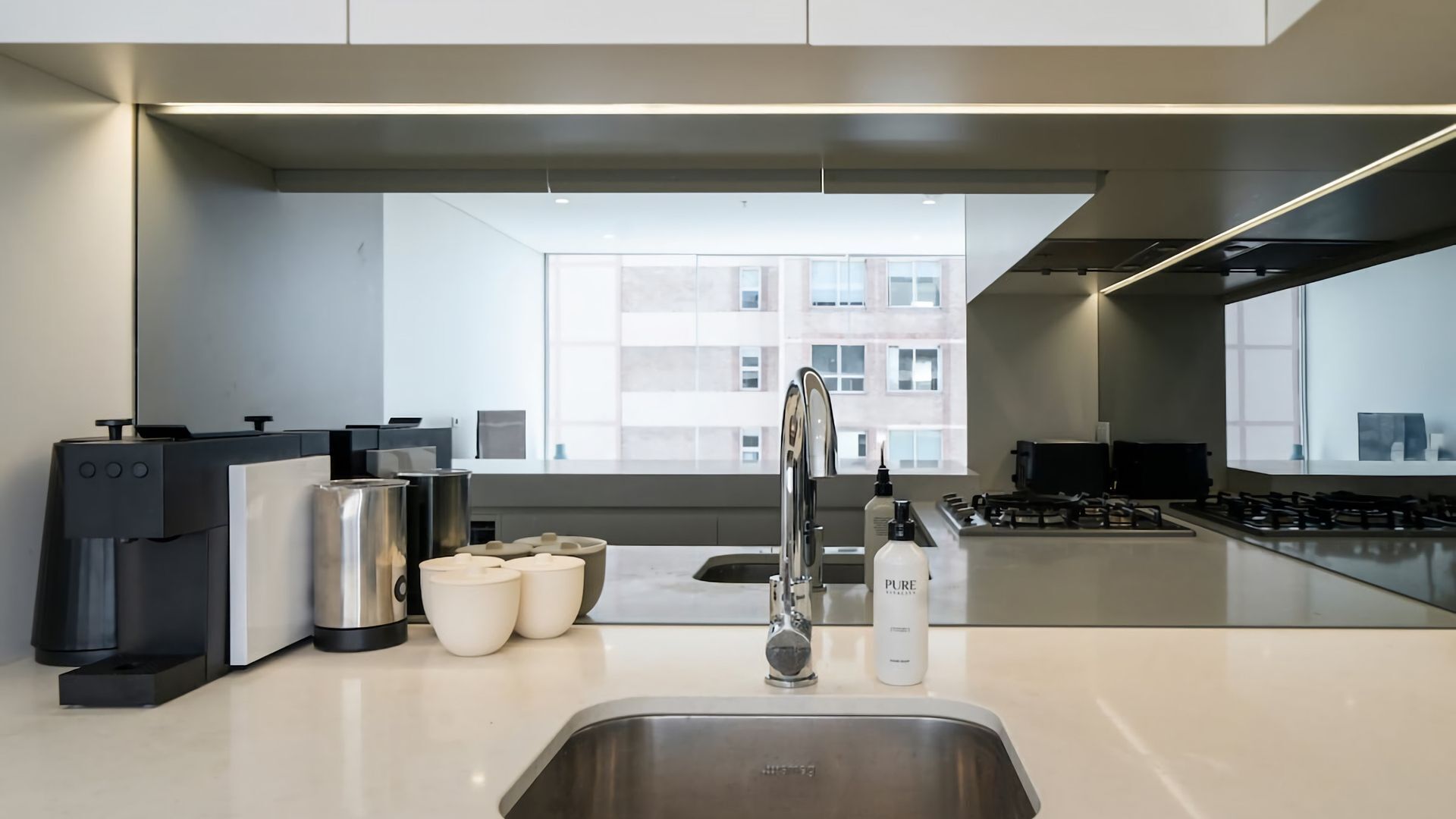 A modern kitchen with a stainless steel sink, a coffee machine, and a range hood.
