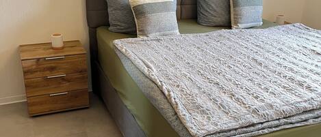A bedroom with a bed, a nightstand, a wooden dresser, and a fur rug.