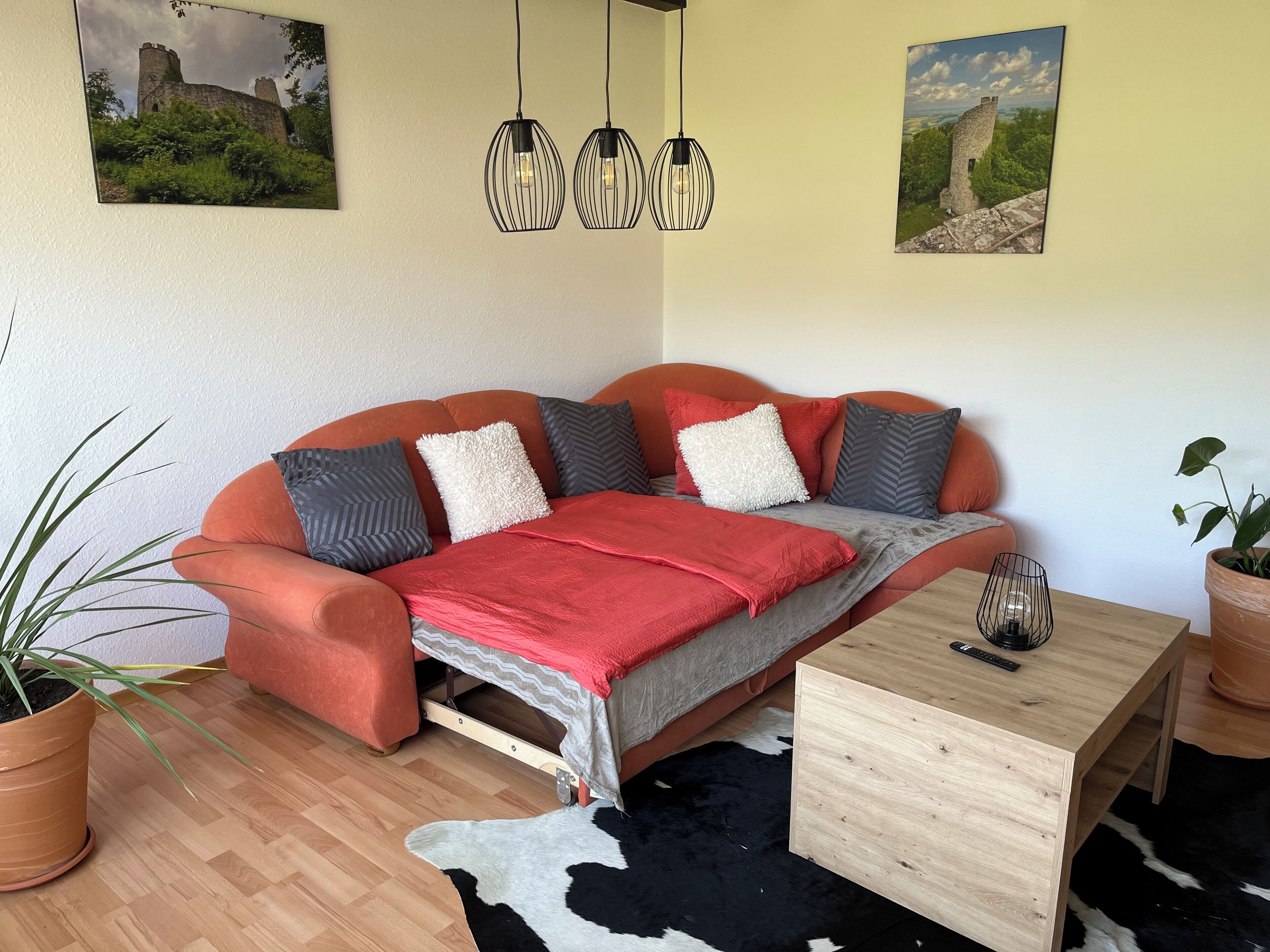 Ein gemütliches Wohnzimmer mit einer Couch, einem Couchtisch und zwei wandmontierten Pendelleuchten.
