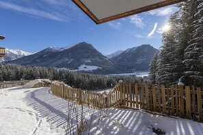 Een besneeerd landschap met een houten hek en een helder uitzicht op besneeuwde bergen.