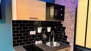 A modern kitchen with black tiled backsplash, wooden cabinets, a stainless steel sink, and a built-in microwave. - ★ Studio Grévy ★ fully equipped - Heart of downtown - Wifi fiber - Netflix (Dole)