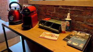 A kitchen counter with a red kettle, a coffee maker, a hand hygiene gel, and a magazine. - ★ Studio Grévy ★ fully equipped - Heart of downtown - Wifi fiber - Netflix (Dole)