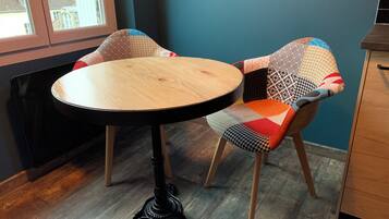 A round wooden table with a black metal base, positioned between two chairs with patterned upholstery.