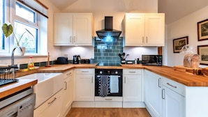 A modern kitchen with white cabinets, a built-in oven, and a window with blinds. - Lodge in Soberton Near South Downs Riding (Southampton)