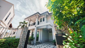 A modern two-story building with a balcony, stone pillars, and a tiled entrance area. - Patak 3 Bedroom Private Pool Villa (Karon)
