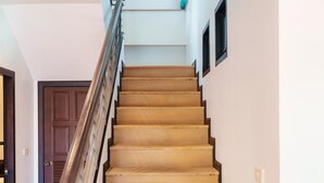 A wooden staircase with a handrail, leading to a landing with a framed picture. - Patak 3 Bedroom Private Pool Villa (Karon)