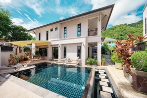 Een modern herenhuis met zwembad, terras en een weelderige tuin.