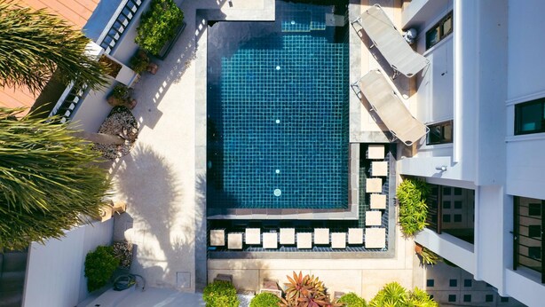 An aerial view of a modern hotel with a central swimming pool, surrounded by lounge chairs and potted plants. - Patak 3 Bedroom Private Pool Villa (Karon)