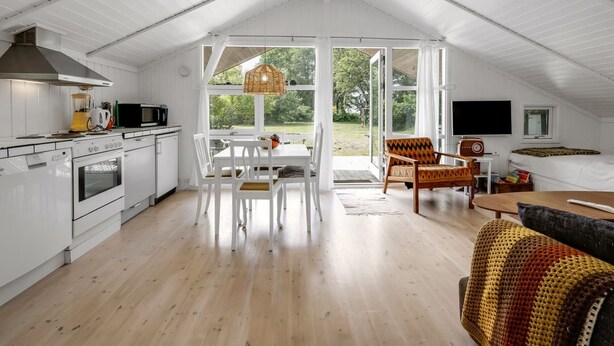 Un loft spacieux avec un plafond haut, une cuisine équipée d’appareils modernes, un coin repas avec une table et des chaises, un coin salon confortable avec un canapé à motifs et une grande fenêtre donnant sur l’extérieur.