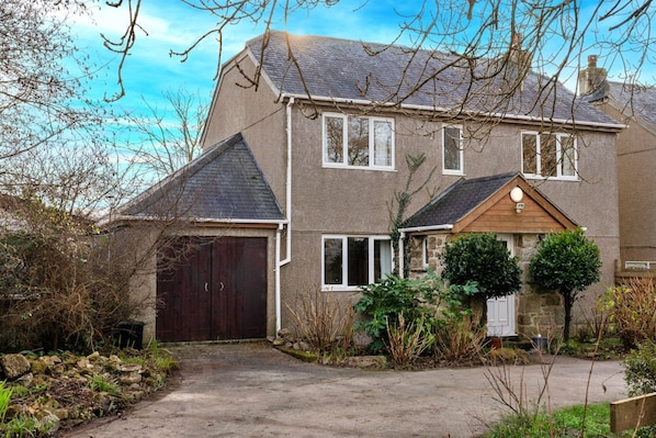 A two-story house with a garage, a front porch, and a stone wall.
