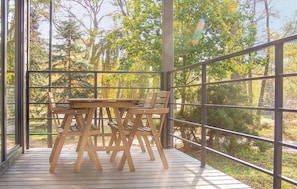 A wooden deck with a table and chairs, surrounded by metal railings, overlooking a forested area. - Holiday Homes With a Lake View (Zlocieniec)