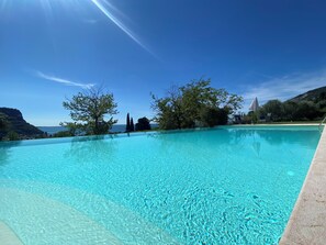 A clear blue infinity pool with a view of the sea and mountains.