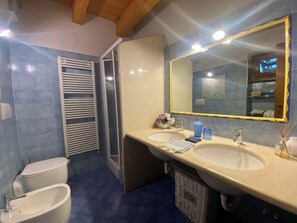 A bathroom with two sinks, a toilet, and a shower.