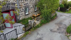Un edificio de piedra con una puerta roja y una pequeña mesa con sillas afuera.