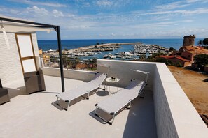 A rooftop terrace with two sun loungers and a small table, overlooking a marina and the sea. - Donna Rosalía Sea View Apartment with terrace/solarium included. (Trabia)
