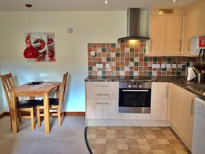 A kitchen with a Bosch oven, wooden cabinets, a tiled backsplash, and a dining area with a table and chairs.