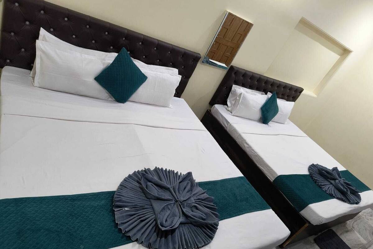 Two twin beds with dark headboards, white linens, teal pillows, and decorative teal and gray fabric accents.