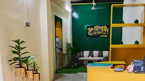 A reception area with a yellow desk, green wall art, and potted plants. - Hotel Kashi Paradise (Varanasi)