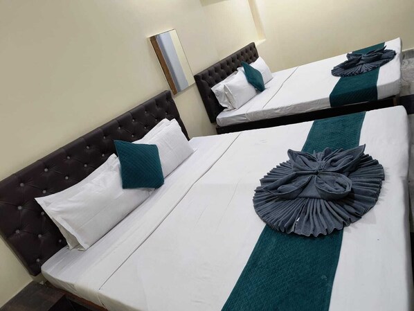 Two twin beds with dark headboards, white linens, teal pillows, and a teal runner.