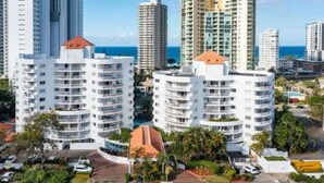 Un edificio residenziale a grattacielo con numerosi balconi, immerso nel verde e circondato da altri edifici di grandi dimensioni.