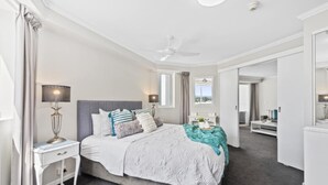 Una camera da letto moderna con un letto, comodini, una ventola a soffitto e vista sull'esterno.