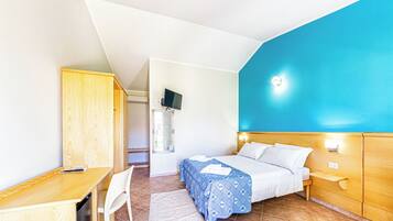 A bedroom with a bed, a desk, a chair, a wardrobe, and a TV on the wall.