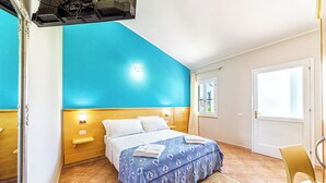 Ein Schlafzimmer mit Bett, Nachttisch, Fenster und Tür.