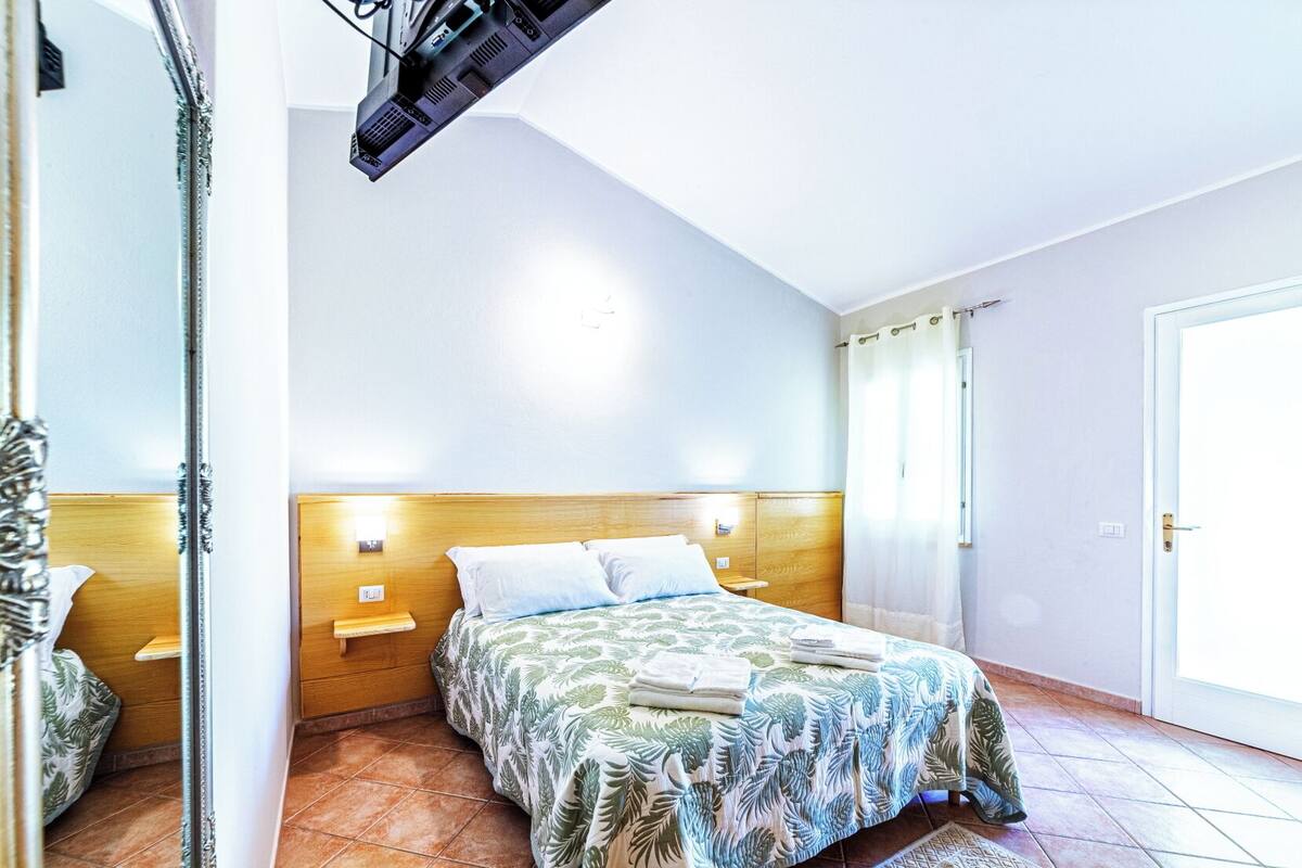 A bedroom with a bed, wooden headboard, bedside tables, and a mirror.