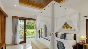 Ein Schlafzimmer mit Baldachinbett, einer Bank, einem Nachttisch mit Lampe und Blick ins Freie.