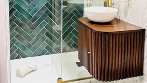 A modern bathroom with a glass shower enclosure, a marble-tiled floor, and a wooden vanity with a white sink. - L'Émeraude - Comfortable studio + private parking (Metz)