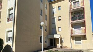 A multi-story residential building with balconies, a central entrance, and a street in front. - L'Émeraude - Comfortable studio + private parking (Metz)