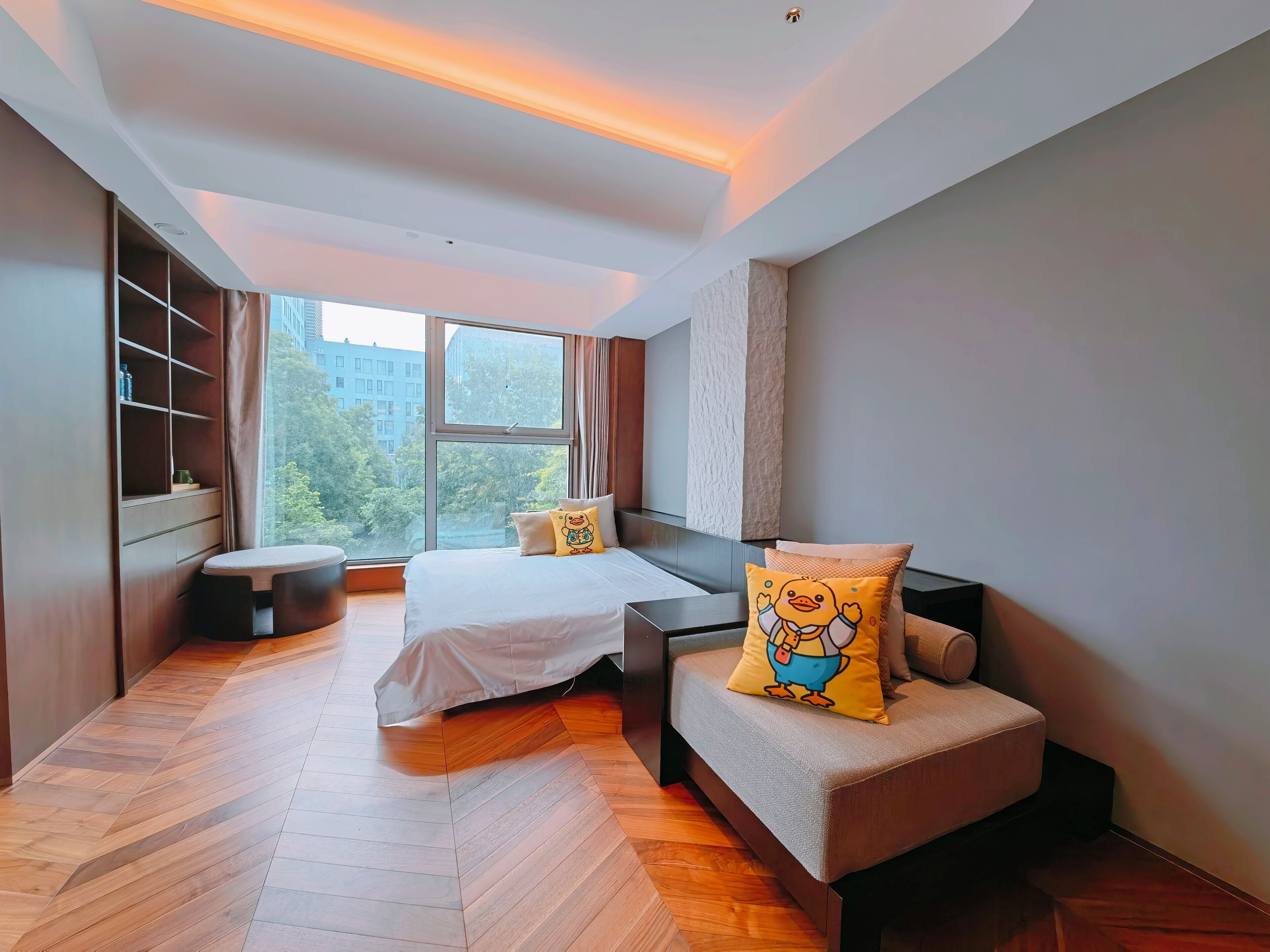Une chambre moderne avec une grande fenêtre, un lit, un canapé et une petite table.