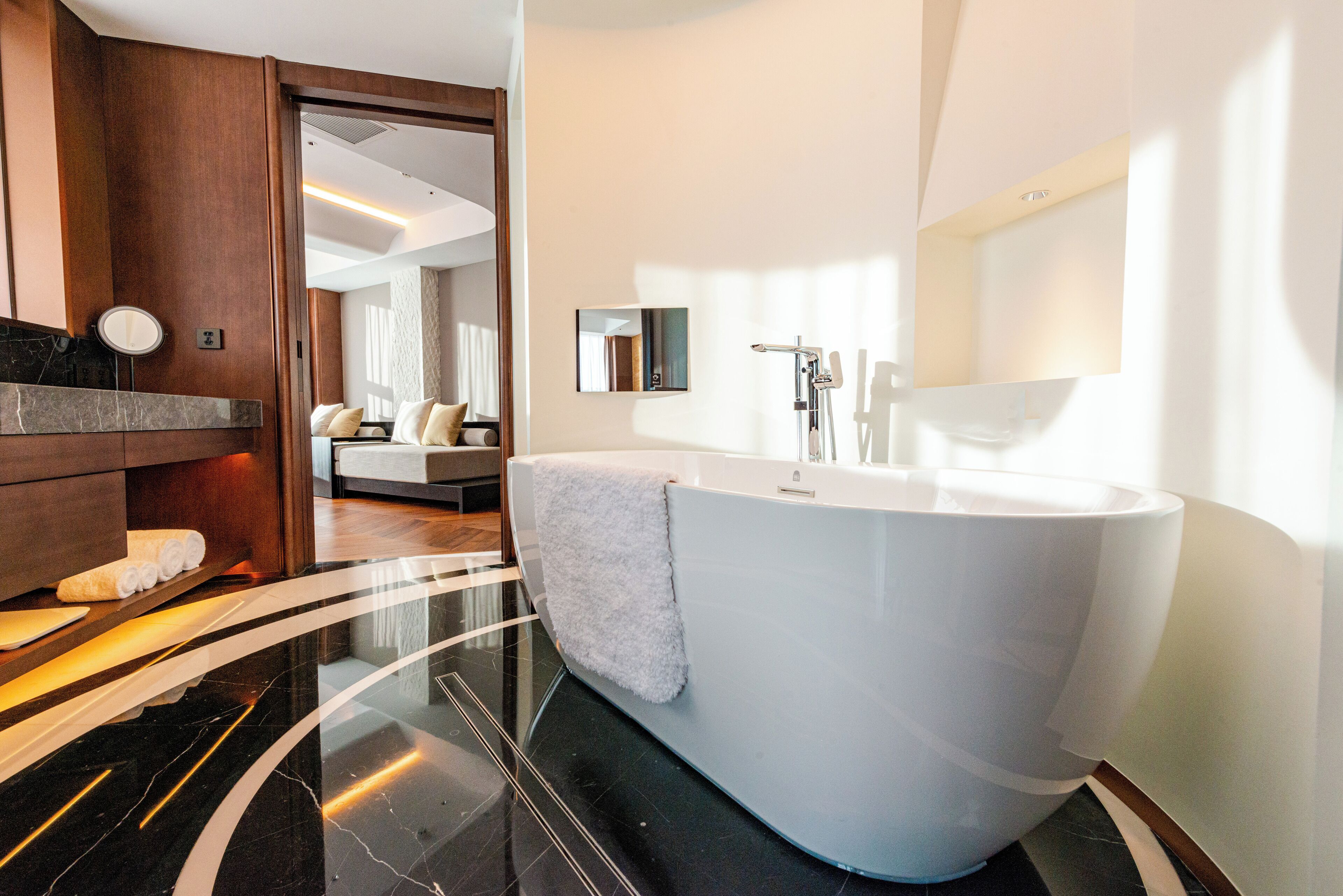A modern bathroom with a large bathtub, a mirror, and a vanity area.