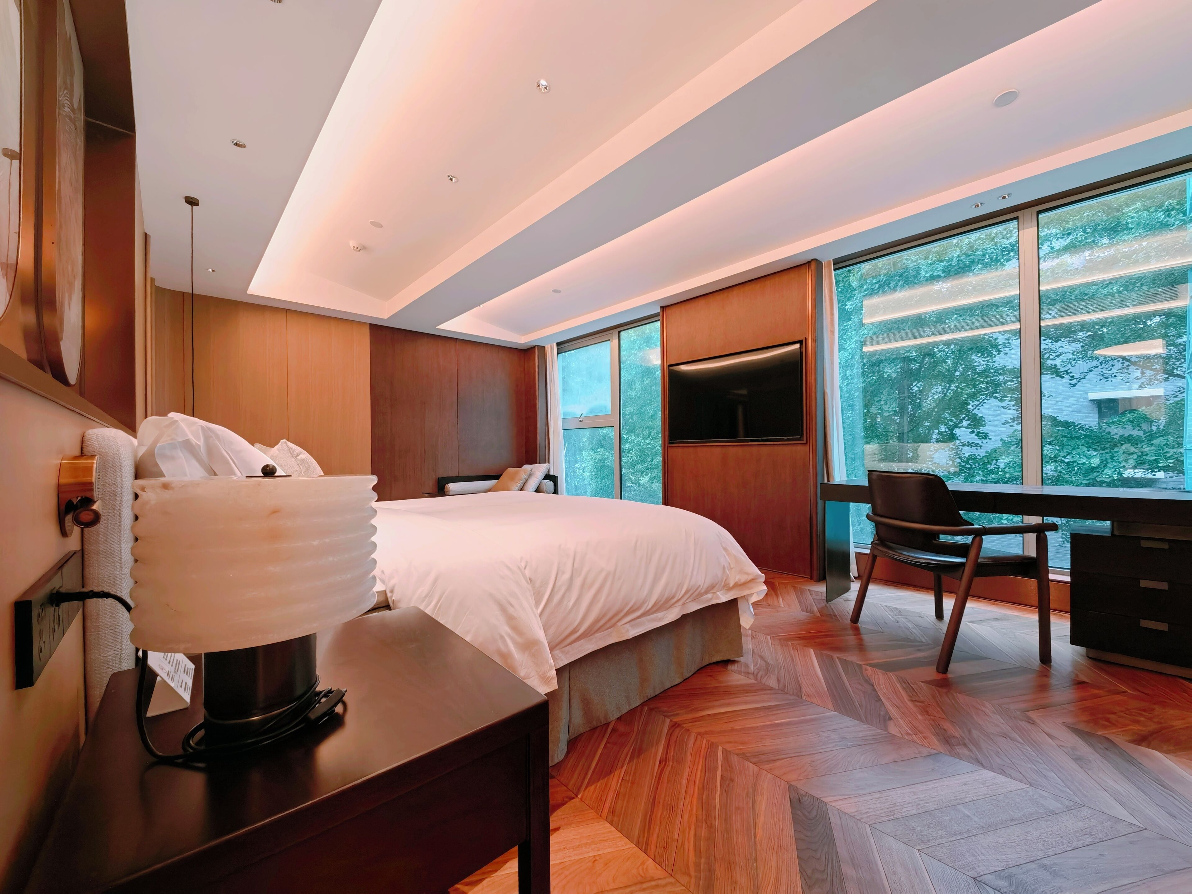 Una habitación de hotel moderna con una cama grande, un escritorio y una televisión.