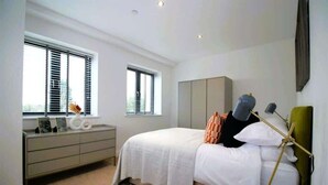 Un dormitorio con cama, cómoda y dos ventanas con persianas.