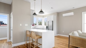 A modern kitchen with a white island, bar stools, and a large window.