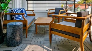 A wooden deck with outdoor furniture, including a sofa and chairs, and a potted plant.