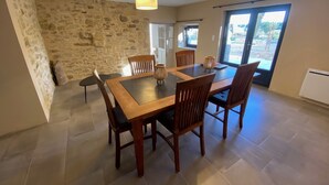 Un coin repas avec un mur en pierre, une table en bois et des chaises.