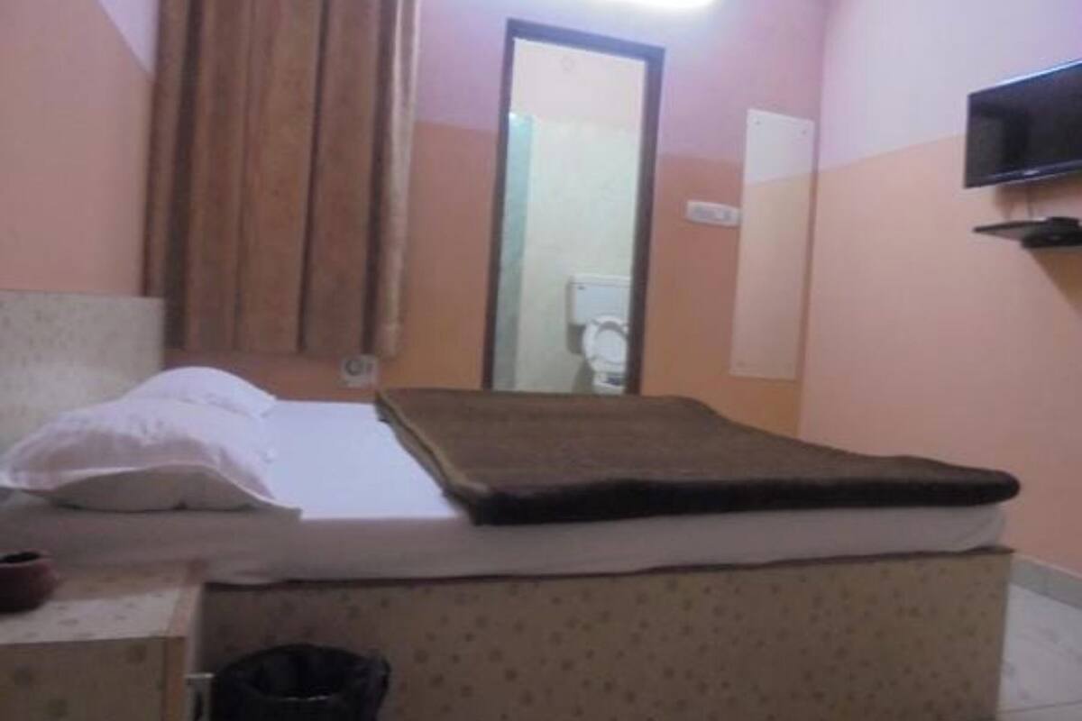 A bedroom with a bed, a television mounted on the wall, and a mirror.