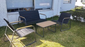 An outdoor seating area with a sofa and two chairs, a small table, and a window with blinds. - Casa Maia, (Arcozelo)