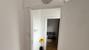 A hallway with a clock on the wall, a door leading to another room, and a flower vase. - Casa Maia, (Arcozelo)