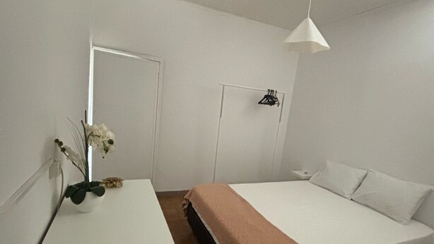 A minimalist bedroom with a bed, a bedside table, a hanging light, and a door. - Casa Maia, (Arcozelo)