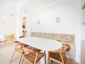 A dining area with a round table and wooden chairs, white walls, and a patterned wall divider.