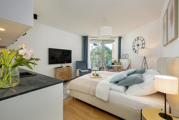 Une chambre à coucher moderne, équipée d’un lit, d’une table de chevet, d’une télévision et offrant une vue sur l’extérieur.