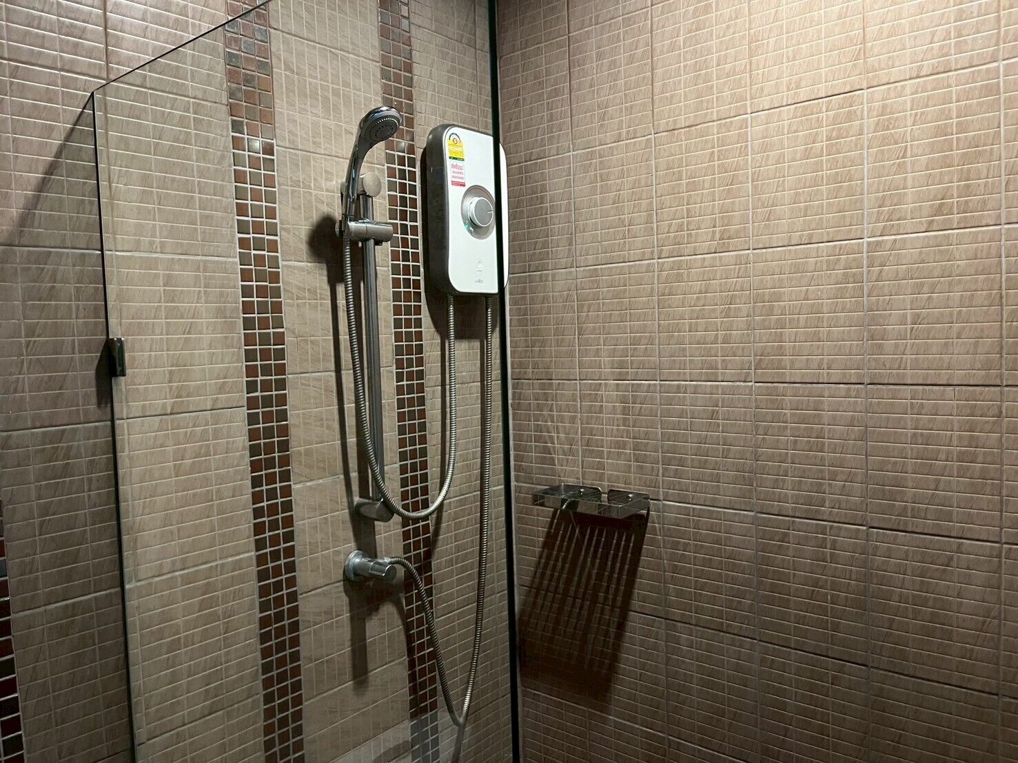 A shower with a handheld showerhead and a wall-mounted control panel.